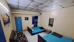 Quarto com duas camas, um sofá, uma TV e um ventilador de teto.