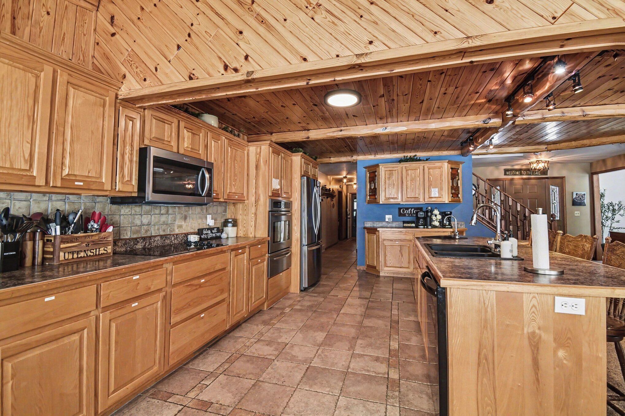 A spacious kitchen with wooden cabinets, stainless steel appliances, and a tiled floor.