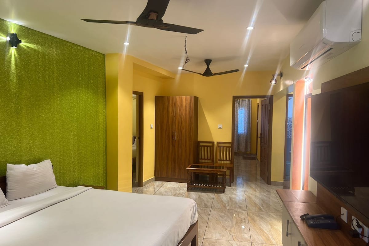A hotel room with a bed, a desk with a telephone, a television, and a ceiling fan.