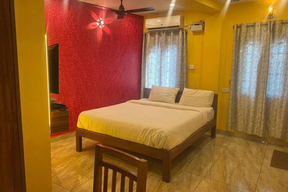 A bedroom with a bed, a ceiling fan, an air conditioning unit, and curtains.