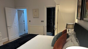 Een slaapkamer met een groot bed, een bedlampje en een deur naar een badkamer.