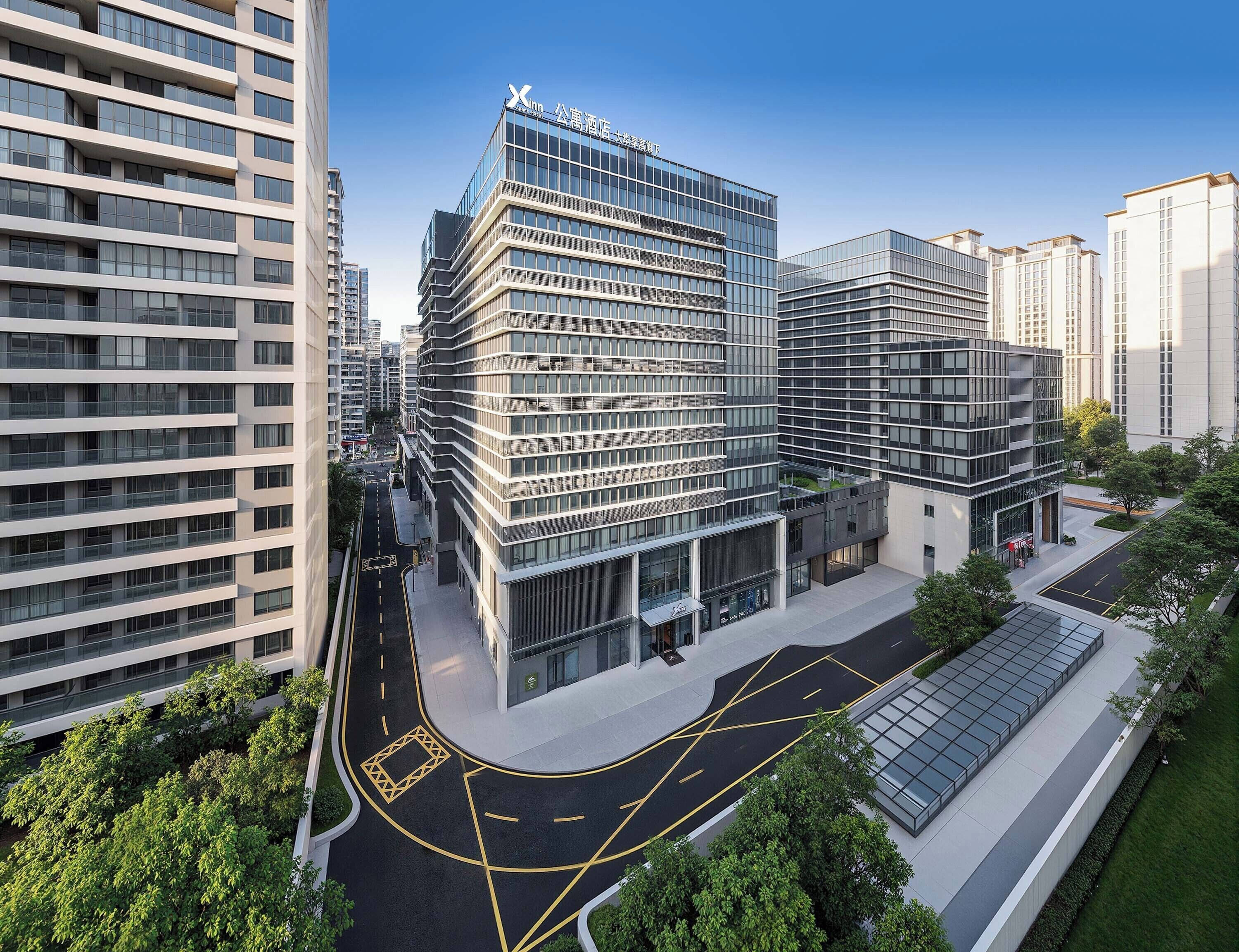 A modern hotel with a glass facade, multiple floors, and a landscaped courtyard.