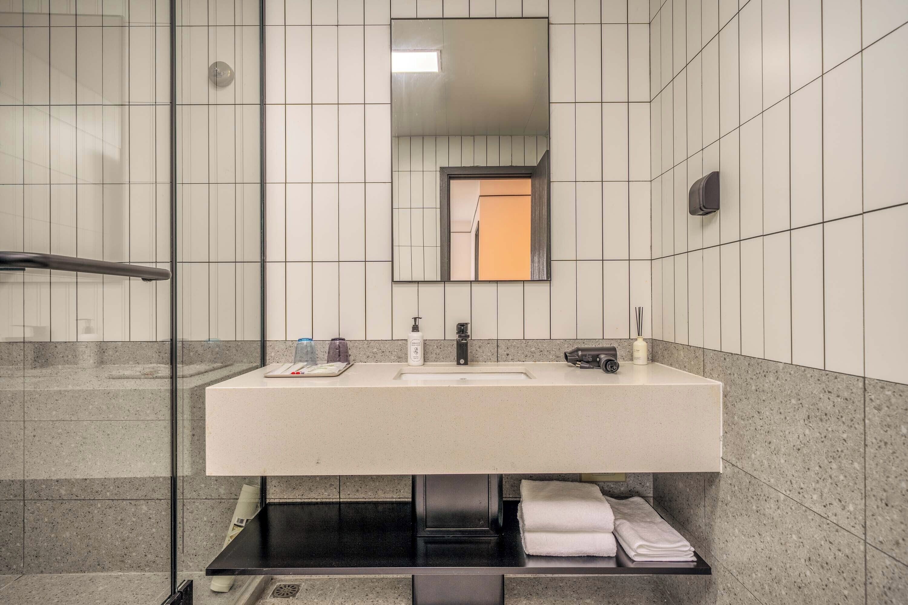A modern bathroom with a large mirror, a sink, and a towel rack.