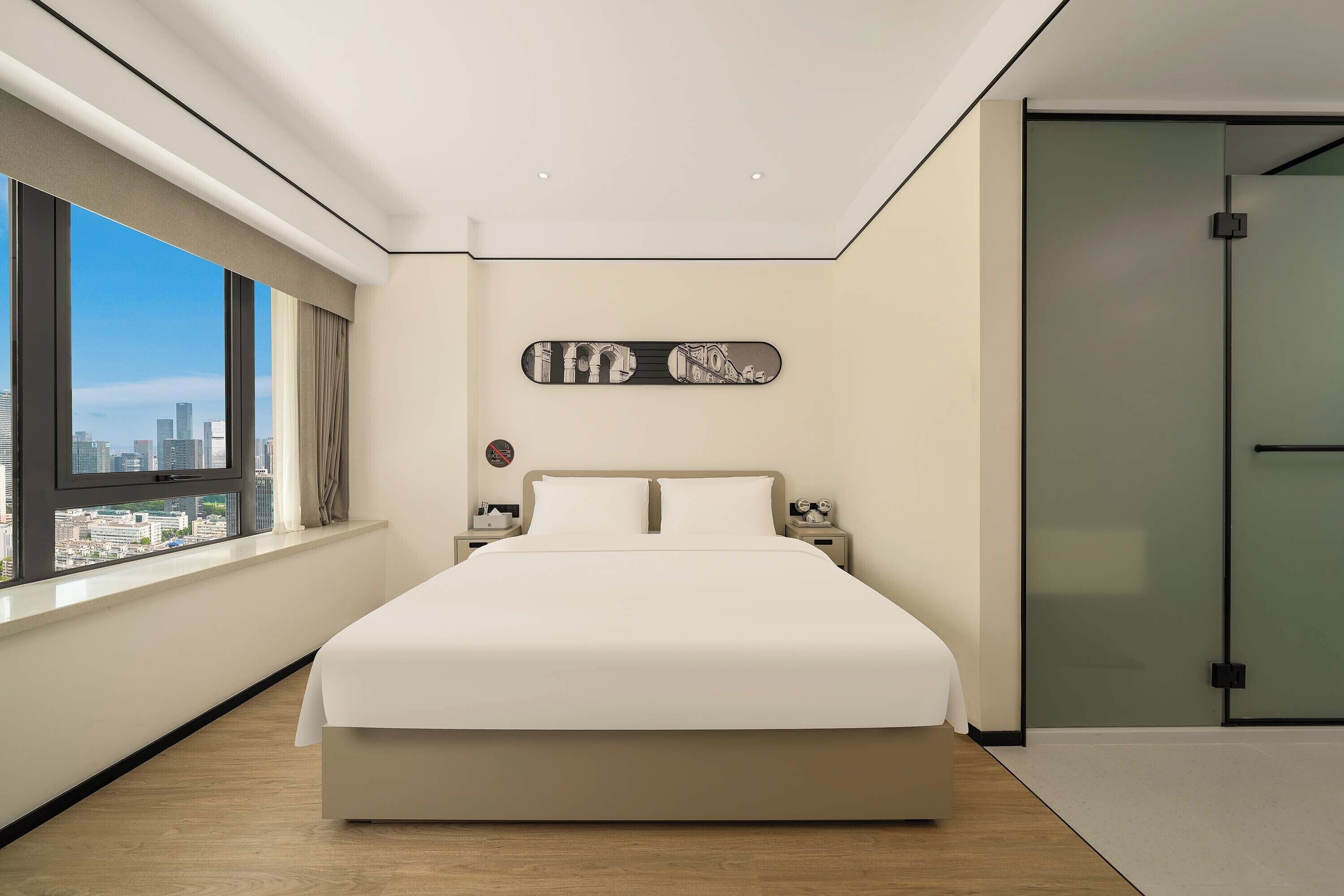Ein modernes Schlafzimmer mit einem großen Bett, Blick auf die Stadt und minimalistischer Einrichtung.