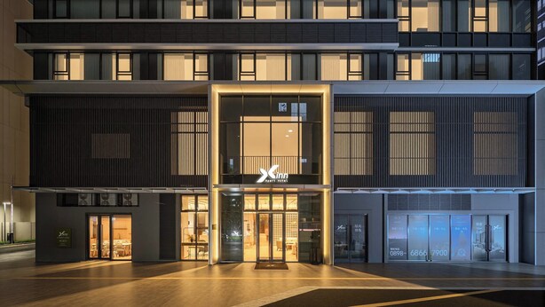 Ein modernes Hotel mit markanter Fassade, mehreren Etagen und guter Beleuchtung.