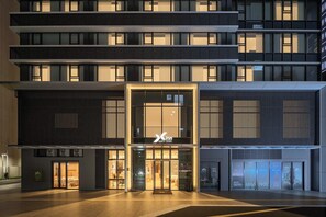 A modern hotel with a prominent entrance, multiple floors, and a well-lit facade.