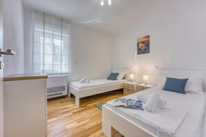 Una habitación de hotel con cama, mesitas de noche, un ventanal y una obra de arte colgada en la pared.