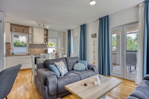 A modern living room with a grey sofa, wooden coffee table, and a dining area with a white table and chairs. - Villa Ancora - Merope Apt /w Jacuzzi & Terrace, Nerezine, Croatia (Nerezine)