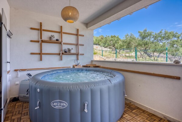 Una stanza spa con vasca idromassaggio, scaffali in legno e vista sugli alberi.