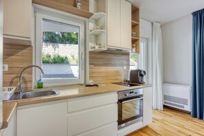 A modern kitchen with a built-in oven, a coffee maker, and a window with a view of greenery. - Villa Ancora - Merope Apt /w Jacuzzi & Terrace, Nerezine, Croatia (Nerezine)