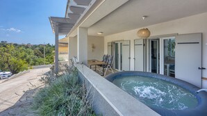 Uma varanda com hidromassagem, área de estar ao ar livre e vista para a paisagem circundante.