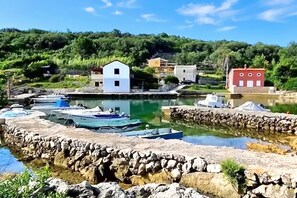 Un pueblo costero con barcos amarrados, muros de piedra y edificios de estilos arquitectónicos variados.