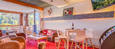 Una sala de estar moderna con chimenea, zona de estar y una mesa de comedor con copas de vino.