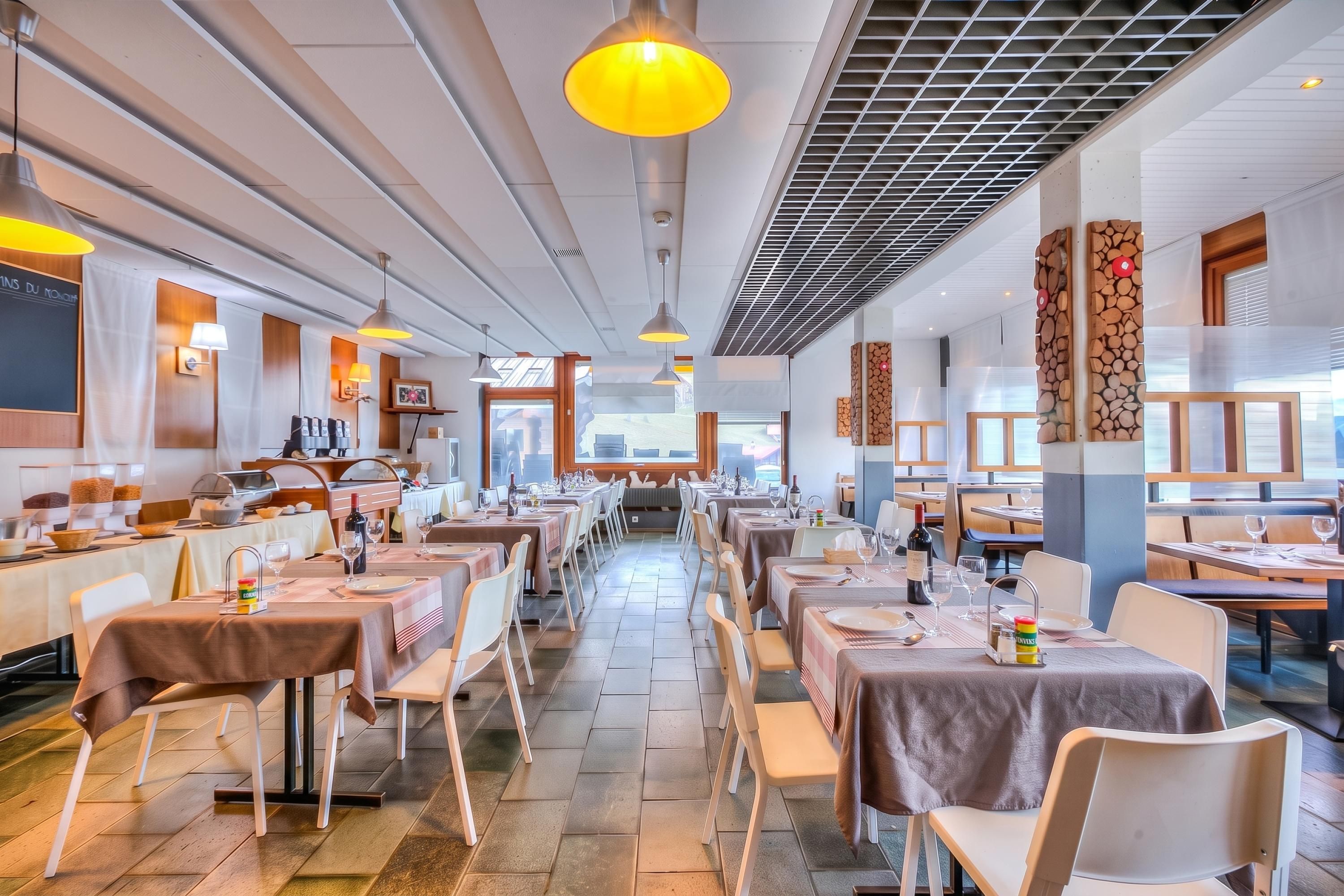 A spacious restaurant with multiple dining tables and chairs, a buffet area, and a view of the outdoors.