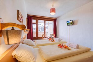 Une chambre d’hôtel avec deux lits, un téléviseur fixé au mur et une fenêtre donnant sur un paysage enneigé.
