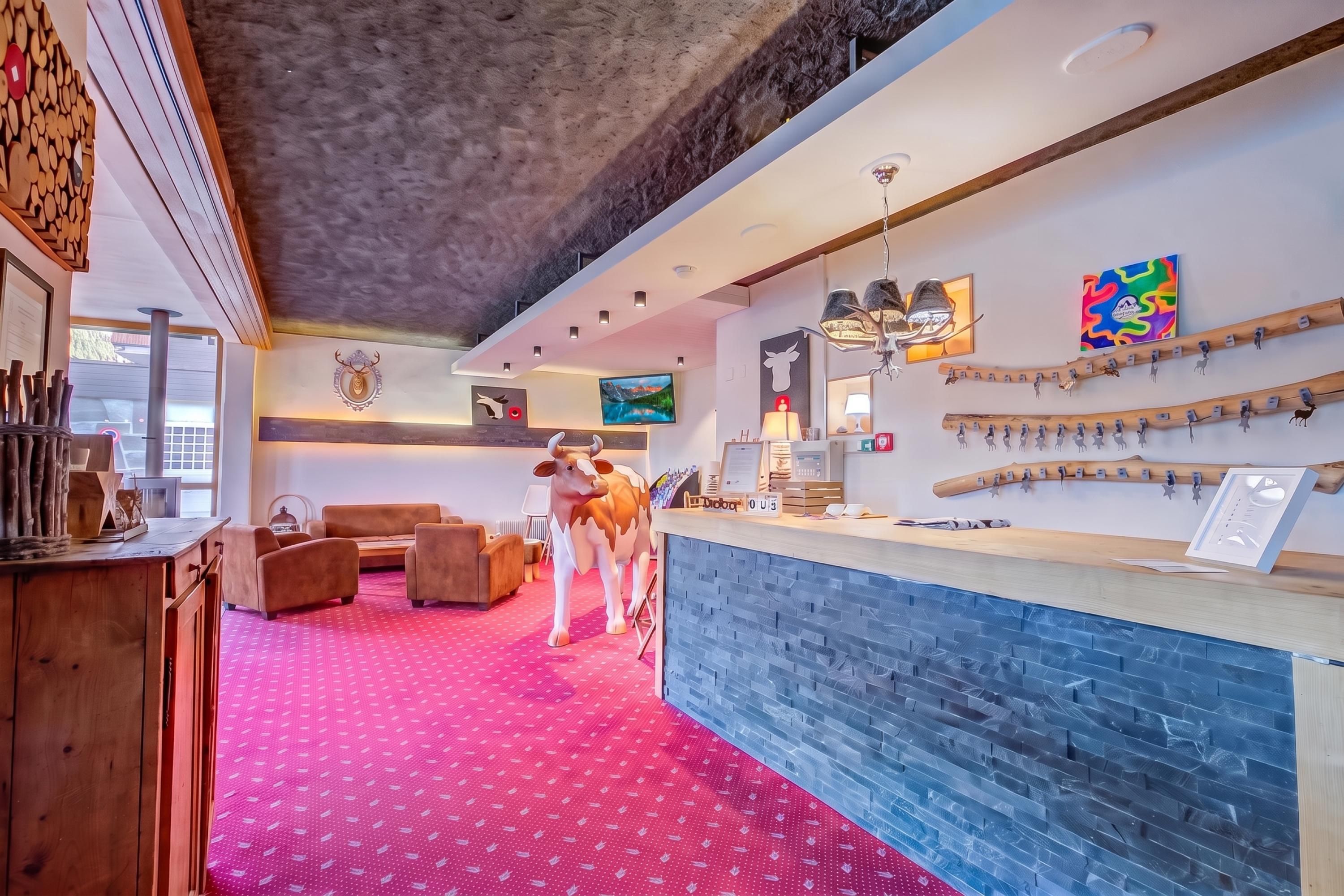 Eine Hotelhalle mit rotem Teppich, Holzmöbeln, einem Empfangsbereich und Wanddekorationen.