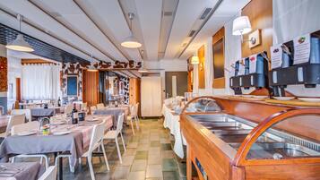 Ein Restaurant mit mehreren Speisetischen, einer Buffetinsel und einer an der Wand befestigten Kaffeestation.