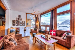 Una sala de estar acogedora con chimenea, un sofá, una mesita de centro y un ventanal con vistas a la montaña.