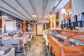 Un restaurante con varias mesas para comer, una zona de bufé y una estación de café montada en la pared.