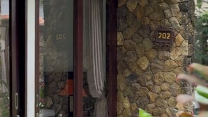 A building with a stone facade, a glass door with a curtain, and a number '202' sign. - 12 Bedroom Villa For Group (Badung)