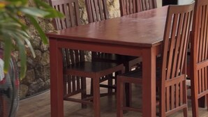 A wooden dining table with six chairs, set against a stone wall. - 12 Bedroom Villa For Group (Badung)