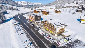 A snow-covered village with buildings, a winding road, and parked cars. - Hotel Relais Alpin Twin Room Ski In-Out 5 129, Les Mosses, Switzerland (Les Mosses)