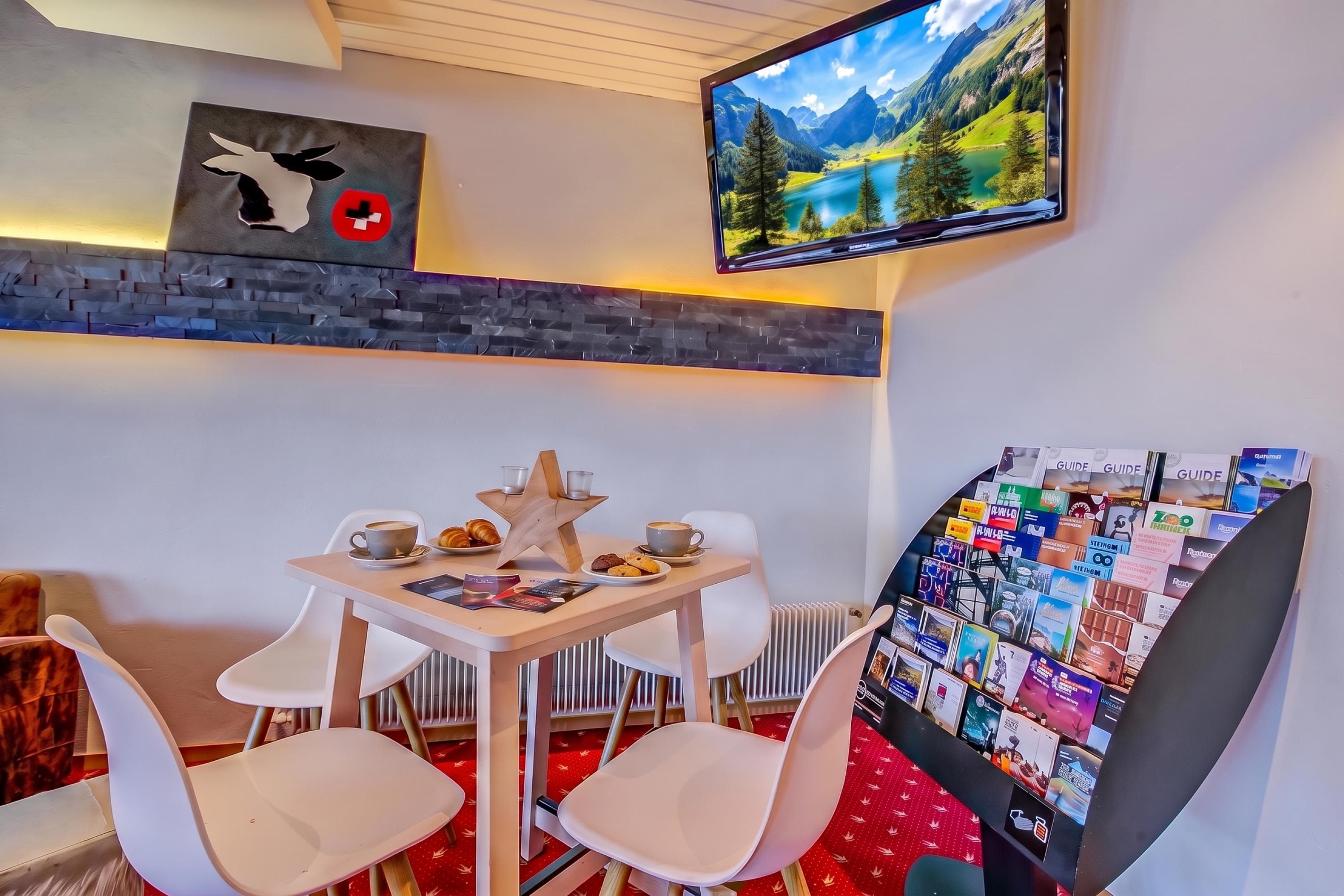 Ein gemütliches Zimmer mit gedecktem Tisch für zwei Personen, einer sternförmigen Dekoration und einem an der Wand montierten Fernseher, der eine schöne Landschaft zeigt.