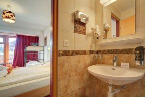 Ein Hotelzimmer mit Etagenbett, einem Badezimmer mit Waschbecken und einem Spiegel.