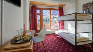 Une chambre avec un lit superposé, un bureau avec un plateau de nourriture, une chaise et une fenêtre avec des rideaux.
