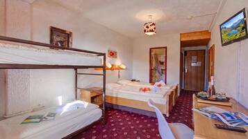 Ein Hotelzimmer mit Etagenbetten, einem Schreibtisch mit Stuhl, einem Fernseher und einem durchgehenden Türspalte sichtbaren Badezimmer.