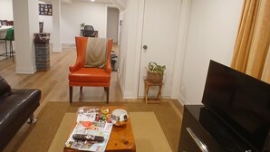 Un salon avec une table basse en bois, un meuble TV noir et un fauteuil rouge.