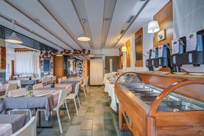 Un restaurante con varias mesas, sillas y una zona de bufé con diversas opciones de comida.