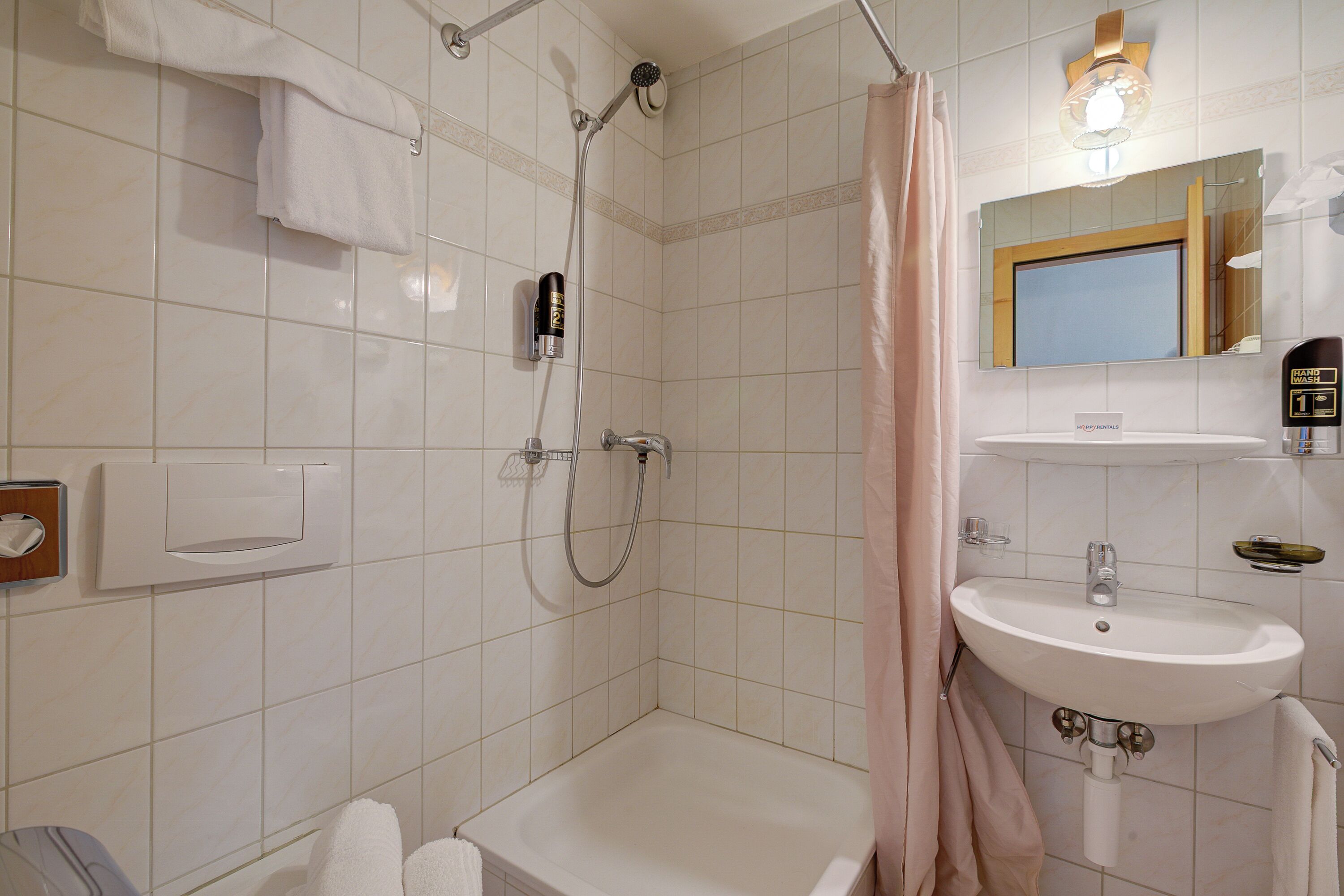 A bathroom with a shower, a sink, and a mirror.