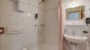 A bathroom with a shower, a sink, and a mirror.