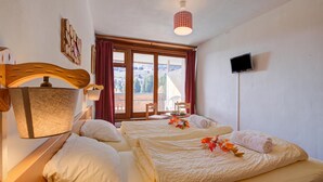 A hotel room with two beds, a TV, a window with curtains, and a wall-mounted lamp. - Hotel Relais Alpin Twin Room Ski In-Out 4 126, Les Mosses, Switzerland (Les Mosses)