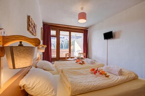 A hotel room with two beds, a TV, a window with curtains, and a wall-mounted lamp. - Hotel Relais Alpin Twin Room Ski In-Out 4 126, Les Mosses, Switzerland (Les Mosses)
