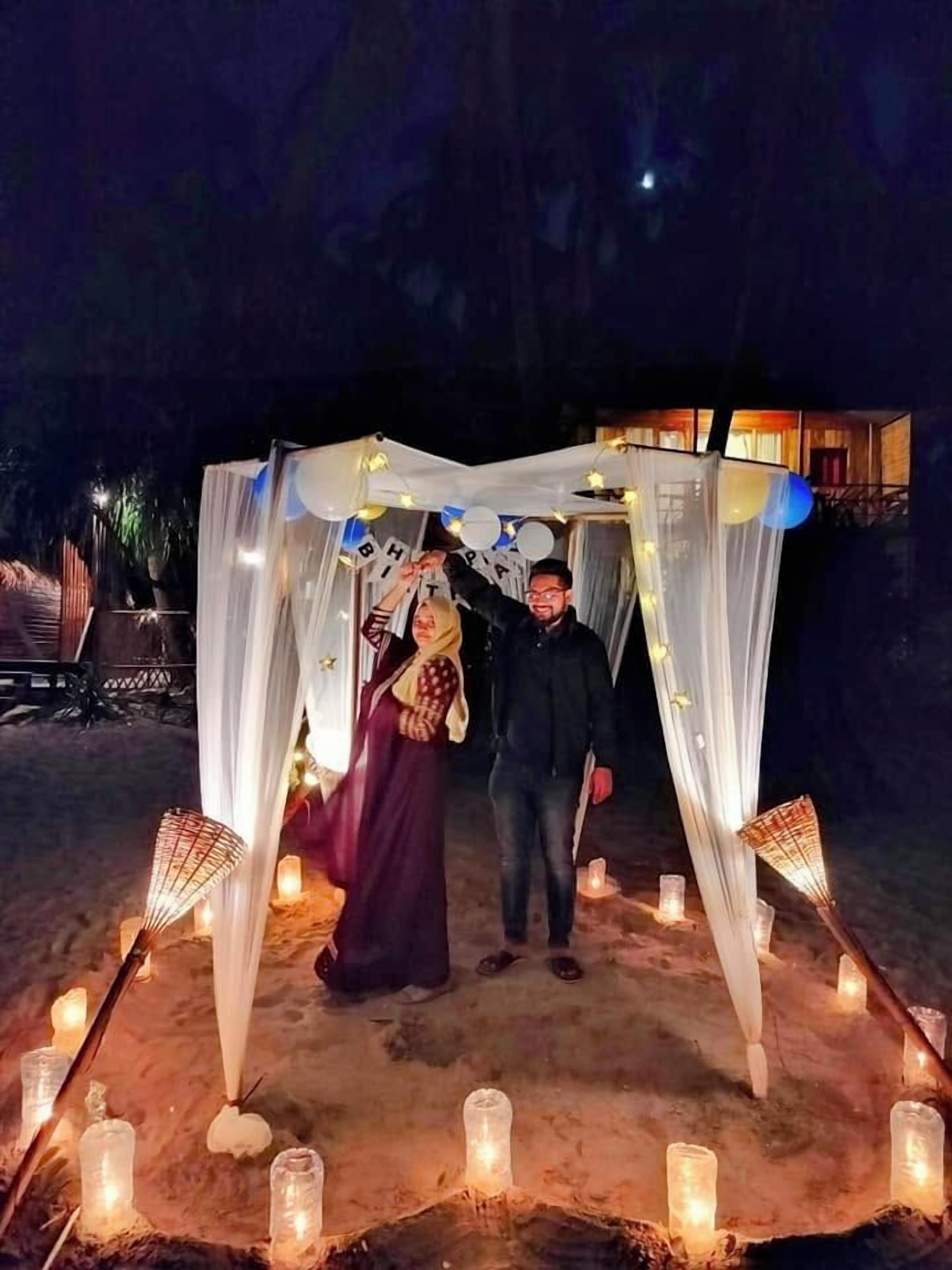 A tent-like structure with draped fabric and candles on the ground.
