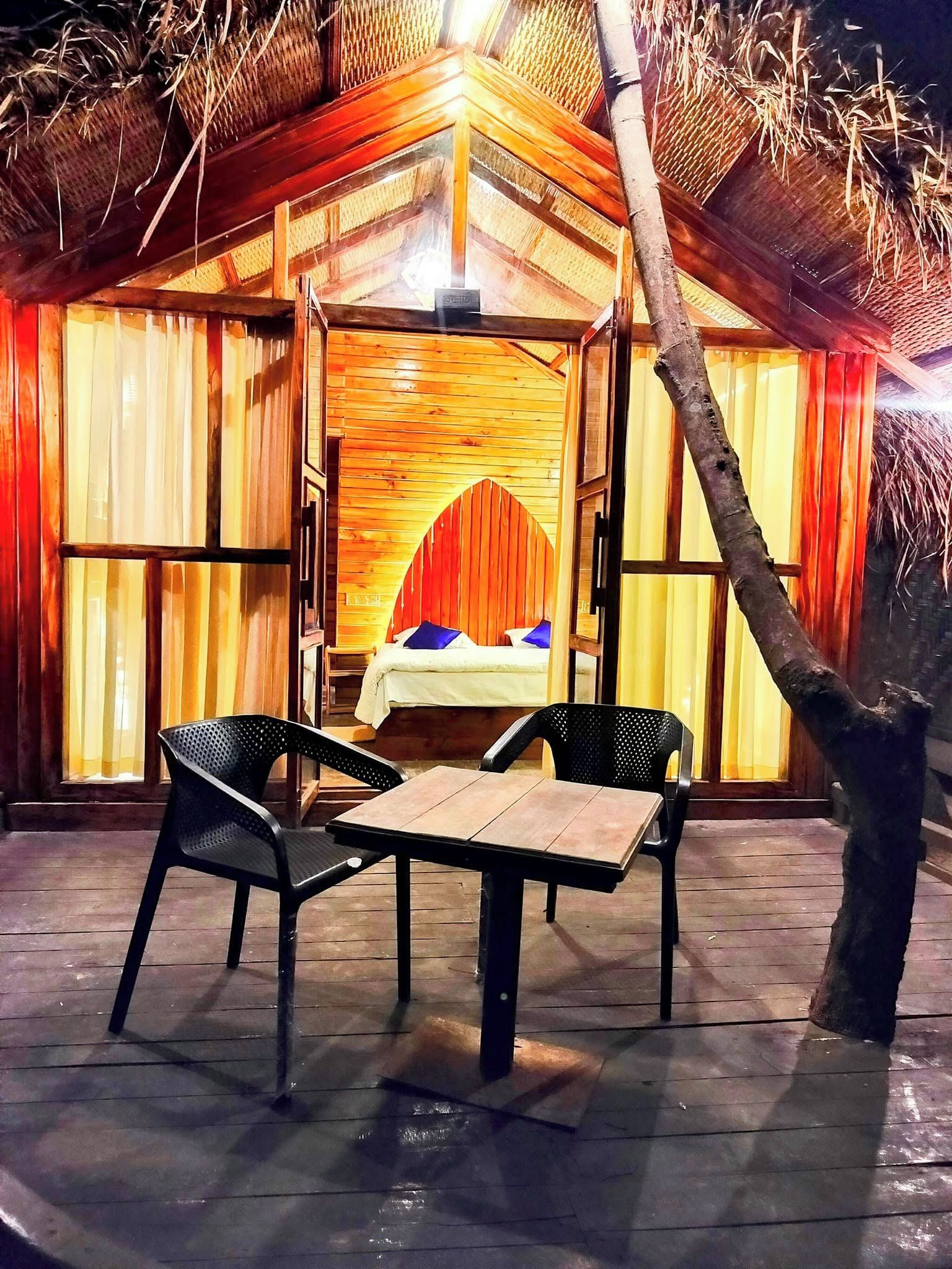 A wooden structure with a bed, two chairs, and a table.