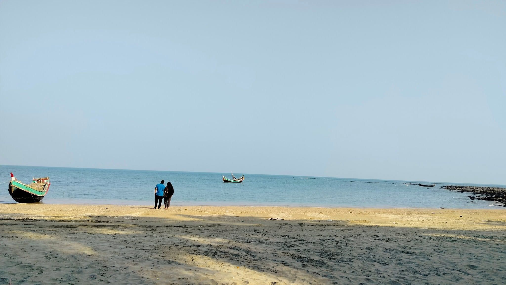 A beach with a boat on the shore and another boat in the water.