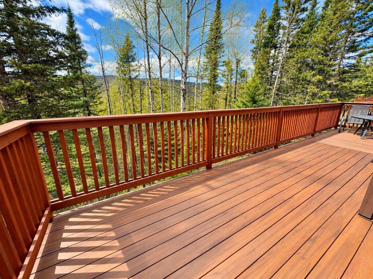 A wooden deck with a railing, surrounded by trees.
