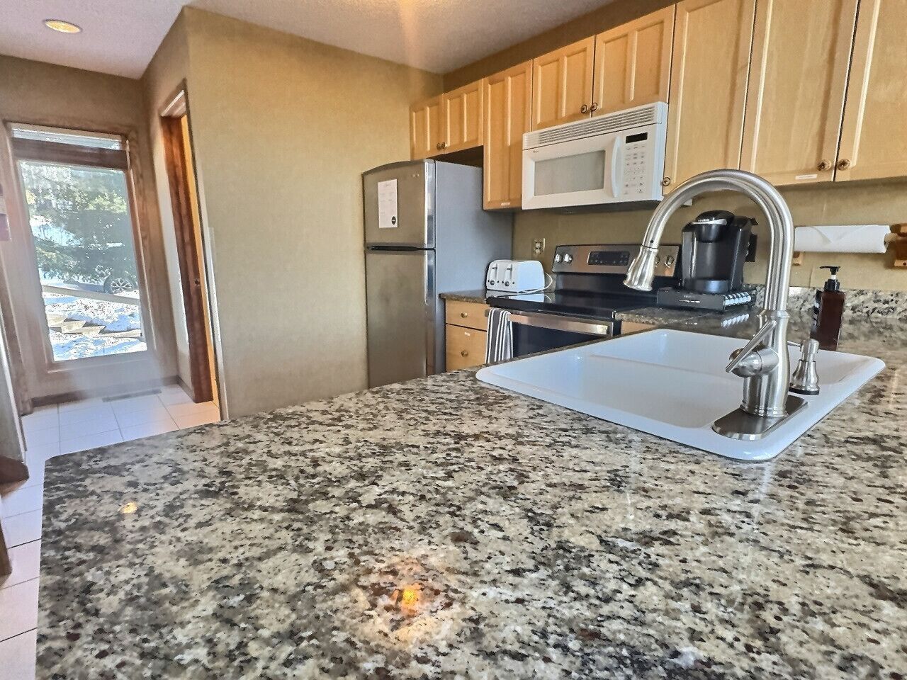 A kitchen with granite countertops, stainless steel appliances, and wooden cabinets.