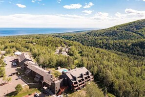 A lodge with multiple buildings, a swimming pool, and forested hills in the background.