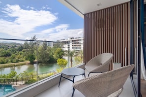Ein Balkon mit Korbmöbeln, Blick auf einen Fluss und Gebäude im Hintergrund.
