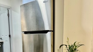A stainless steel refrigerator with a nameplate, a wooden table with a potted plant, and a wooden floor. - Private Entire Guest Suite, 1 min to bus stops to Downtown and many attractions. (Vancouver)