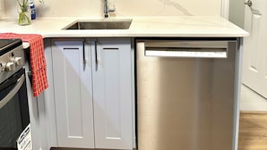 A kitchen with light blue cabinets, a stainless steel Bosch dishwasher, a marble backsplash, and a wooden floor. - Private Entire Guest Suite, 1 min to bus stops to Downtown and many attractions. (Vancouver)
