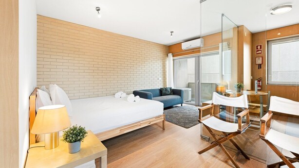 Een moderne hotelkamer met een groot bed, een bank, een kleine tafel en een glazen scheidingswand.