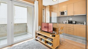 Een moderne keuken met houten kastjes, een magnetron en een kleine eethoek met een stoel en een tafel.