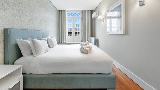 Una camera d'albergo moderna con un letto grande, un comodino, un armadio e vista all'esterno tramite una porta vetrata.