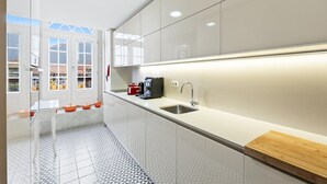 Una cucina moderna con un lungo piano di lavoro, un lavandino e una macchina per il caffè.