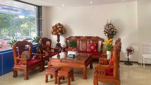 Eine traditionelle Holzmöblierung in einem Raum mit großem Fenster, einem Ventilator und einer Blumenvase.